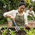 Woman using an Ergonomic Heavy Duty Garden Hand Fork in a vegetable garden to aerate soil.