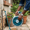 Retractable Portable Garden Hose Reel in use, connecting to faucet for easy watering of outdoor plants.