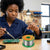 User soldering a circuit board with Tin Lead Rosin Core Solder Wire 100g Reel in a workshop environment.