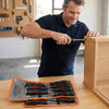 Man using the 7-in-1 Magnetic Percussive Screwdriver Kit to assemble furniture in a workshop.