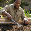 A gardener using the Heavy Duty 3-Prong Hand Rake to cultivate soil in a vegetable garden.