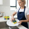 Woman using a Dual-Action Kitchen Cleaning Sponge on a plate in a modern kitchen, showcasing its cleaning effectiveness.