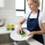 Woman using a Dual-Action Kitchen Cleaning Sponge on a plate in a modern kitchen, showcasing its cleaning effectiveness.