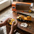 Person controlling the 1:30 Scale Remote Control Construction Crane Truck with the remote on a wooden table.