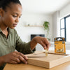 Woman installing Triangular Sawtooth Picture Hanger on a wooden frame with picture hooks in the background.