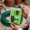 4pcs Connector Set packaging held by hands with a green hose in background for connecting garden hoses.