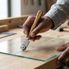 Person using a 130mm Wooden Handle Glass Cutter Pen on a glass sheet for precise scoring.