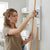 Woman organizing cleaning tools using Wall Mounted Mop and Broom Holder Clip on a wall.
