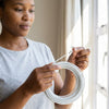Woman holding 3M Flexible Aluminum Curtain Wire Cord and hook, ready to hang curtains.