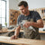 Man using DG-10 Metal Air Dust Blower Gun to clean wood surface in workshop.