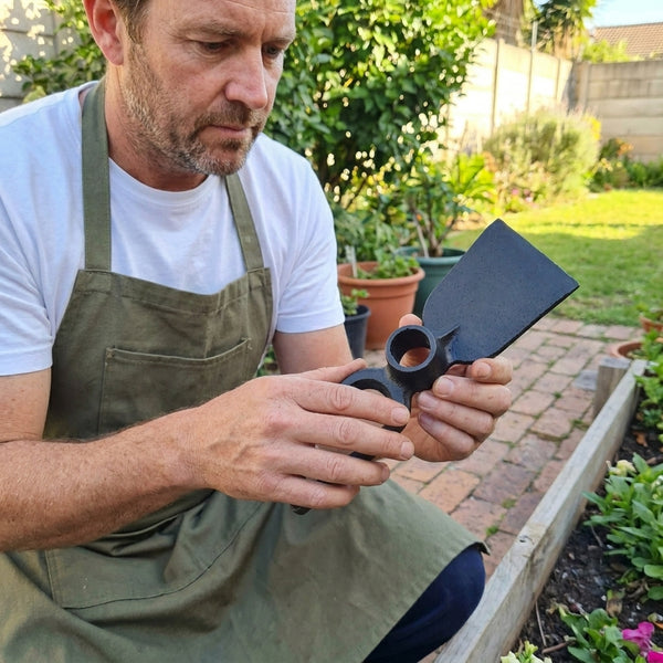 Man using a Carbon Steel Double Headed Garden Hoe-fork in a garden, showcasing its design and functionality.