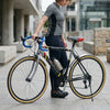 Single Speed Aluminium Alloy Fixed Gear Bike parked by a cyclist in a city setting, showcasing its sleek design and lightweight build.