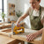 Woman using an Industrial Metal Brad Nail Gun on a piece of wood in a workshop, showcasing upholstery skills.
