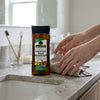 Deep Hydrating Licorice Root Glow Body Oil displayed on a countertop with hands applying the product.