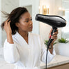 A woman in a robe using the Professional 2400W High Speed Hair Dryer to style her hair at home.