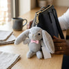 Necktie Rabbit Plush Keychain Pendant clipped to a purse with a cozy atmosphere, featuring a gray bunny with a bow tie.