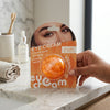 Vitamin C Brightening Under Eye Patches in an eye cream package held by a hand on a marble countertop.