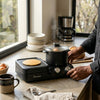 Person using the 5-in-1 Multifunctional Mini Breakfast Machine to prepare breakfast on a kitchen countertop.