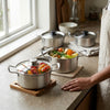 Stainless Steel Round Stock Pot with Lid and vegetables on a kitchen counter, perfect for cooking large batches.