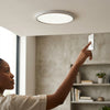 A person adjusting the light switch for a 12W Round LED Surface Panel Light on a modern ceiling.