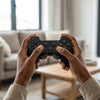 Person holding a PS3 Wired Joystick Game Controller while gaming in a cozy living room setting.
