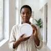A woman holding a 6W Round LED Surface Panel Light inside a bright indoor space.