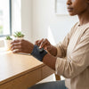 Person using Joint Heating Vibration Massage Wrap on wrist at a desk to relieve discomfort.