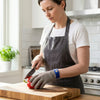 Woman using a knife while wearing Level 9 Stainless Steel Mesh Cut Resistant Glove in a kitchen setting.