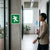 Person walking past an Aluminum Emergency Direction Arrow Sign in a modern office environment.