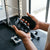 Person holding Ergonomic Anti-Slip Rubber Workout Grips in a gym setting with weights in the background.