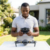 User operating the 998 PRO 4K Dual Camera Foldable Drone remote controller outdoors.