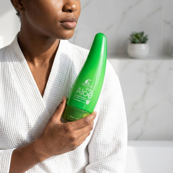 Aloe Vera Soothing Moisture Conditioner bottle held by a woman in a white robe, set in a bright bathroom.
