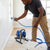 Man using an Airless Paint Sprayer for smooth wall painting in a well-lit room.