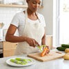 Woman using the 3-Piece Stainless Steel Vegetable Peeler Set to peel a carrot in a modern kitchen.