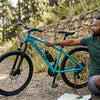 Full Suspension Enduro Mountain Bike with 160mm Travel resting on a trail with a rider checking a map.