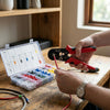 Person using a Mini Multi Cord End Hand Insulated Crimping Tool on a wire with a terminal connector kit nearby.