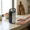 Portable LED Emergency Light Rechargeable Lantern on a kitchen countertop with hands nearby.