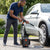 Man using a Wireless Electric Water Gun for Snow Removal & Cleaning to wash a car's wheel.