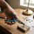 Hand using Long Nose Combination Pliers for Electrical Repair on a wooden surface with screws and hardware in the background.