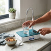 USB Desktop Water Bottle Pump Dispenser in use, filling a glass with water on a kitchen countertop.