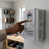 Person adjusting settings on a 7.5kW Three-Phase Solar Pump Inverter mounted on a wall.