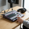 Image of a person using a 7-Channel USB Live Sound Mixer with headphones on a wooden table.