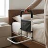 Bedside Grab Bar with Storage Pocket next to a bed, featuring a padded handle and storage pocket for personal items.