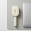 Spray Scalp Massage Comb on a desk beside a laptop, designed for gentle scalp massage and convenient spray functionality.