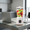 Digital LCD Countertop Blender with fruits on a kitchen table next to a laptop.