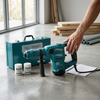 Corded Hammer Power Tool with Carrying Case on concrete floor with tools and accessories nearby.