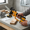 Person using a Cordless Lithium Mini Chainsaw Power Tool Set on wood in a workshop.