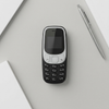 Compact Mini GSM Mobile Phone with Keypad on a gray background with a pen and notebooks.