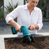 Woman using a Cordless Handheld Garden Cultivator to work soil in a garden bed.