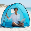 A woman sitting inside a Two Person Beach Tent on the sand, working on a laptop, enjoying a sunny beach day.